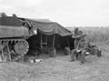 'A tank bivvy on the plains near Carpiquet. Tpr. Dawson getting his hair cut by L/Cpl. Johnnie Davies' 3rd County of London Yeomanry (Sharpshooters), July 1944