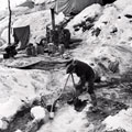 Corporal T Doran from Liverpool breaking the ice of a stream in order to insert a feed pipe for showers, Italy, January 1945