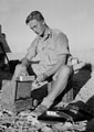 A member of 3rd County of London Yeomanry (Sharpshooters) cooking on a stove in the desert, 1942 (c)