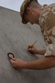 A serviceman sketching the Royal Air Force Police Qualified Police Dog (QPD) badge for a mural on a blast wall, Iraq, 2009