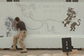Soldier painting blast wall mural, Contingency Operating Base, Basra Air Station, Iraq, 2009