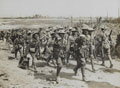 A Vickers machine gun team marching past a working party heading in the opposite direction, 1916