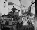 A Sherman tank following a mule train through the main street of Torino Di Sangro, Italy, 2-4 December 1943