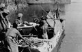 A wounded African soldier being carried by stretcher bearers on to a motor launch, Burma, 1944 (c)