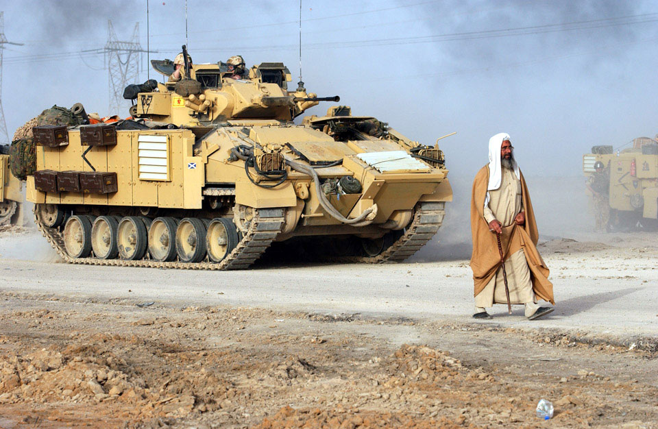 A civilian walks in front of a Warrior Infantry Fighting Vehicle, Iraq, 2003