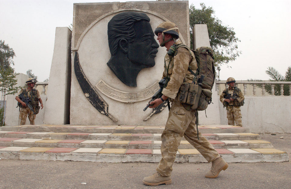 A soldier from 3rd Battalion The Parachute Regiment passes a monument to Saddam Hussein during a patrol in Basra, April 2003