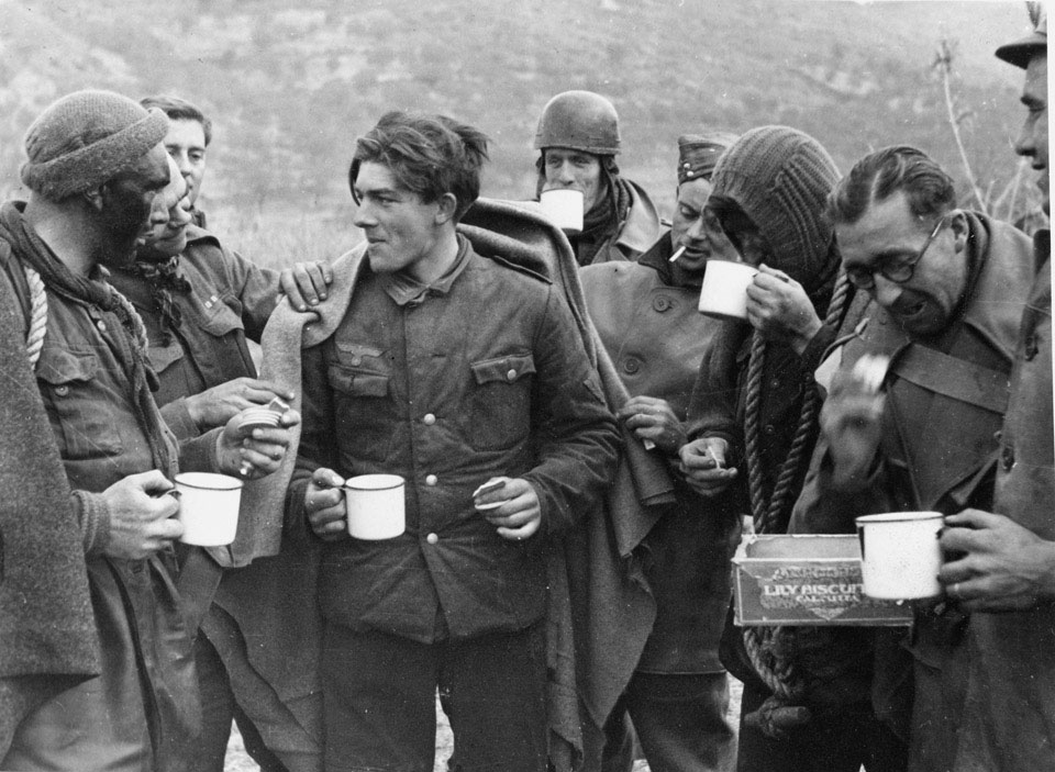 Commandos grouped round a German prisoner, captured on a raid, 11 January 1944