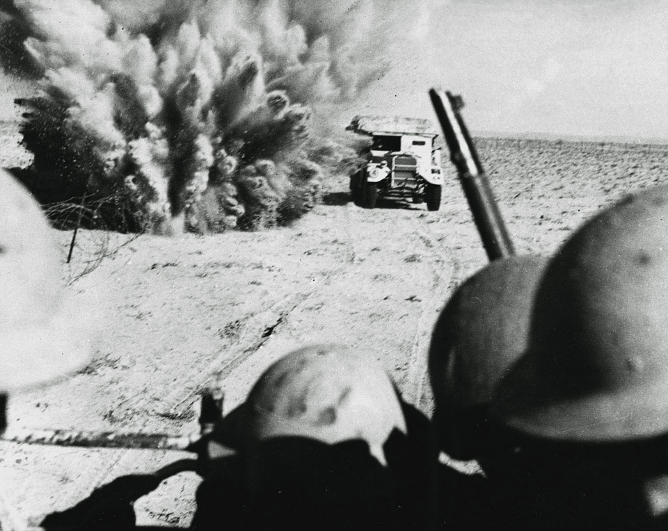 A mine explodes close to a British artillery tractor as it advances through enemy minefields at El Alamein, 1942