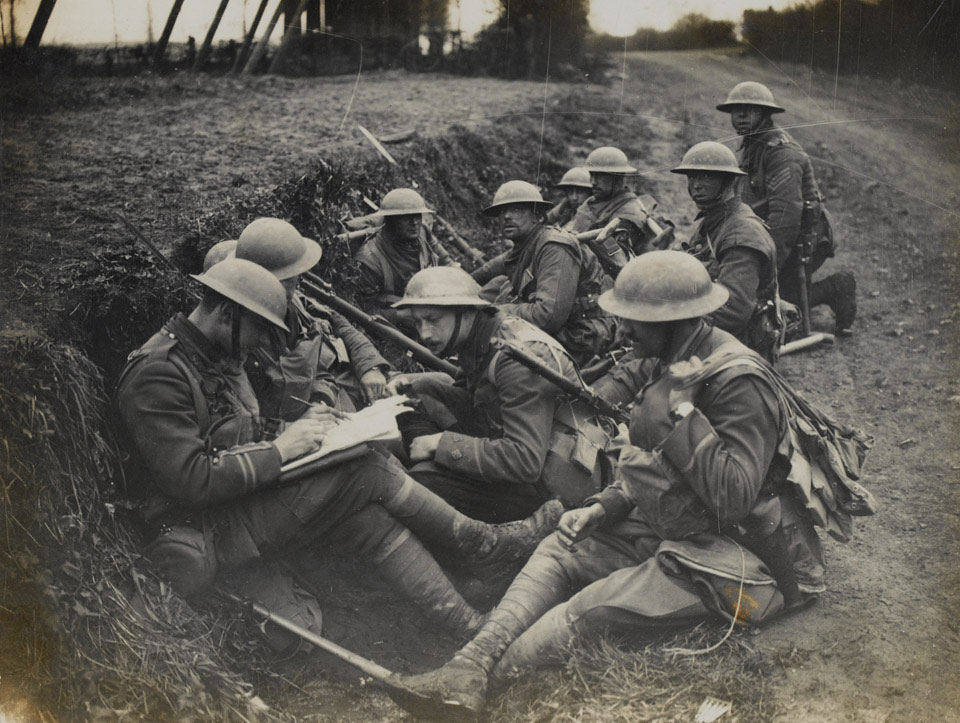 Soldiers from the Middlesex Regiment rest in a ditch as their officers consult a map, 16 April 1918