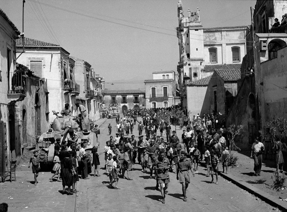 Civilians and British soldiers escort prisoners at Mascalucia, 1943