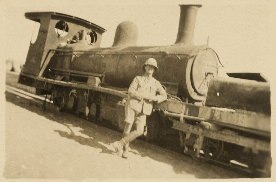 A British soldier leaning against a railway engine on the desert railway, 1917 (c)