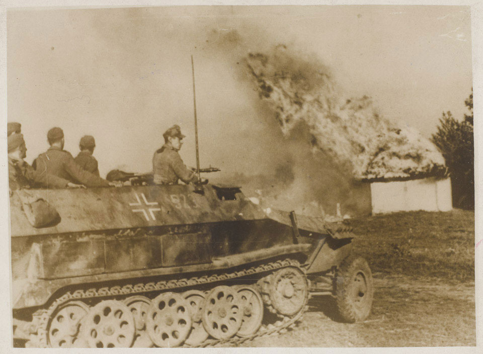 A German half-track driving through a burning Russian village in the Crimea, 1942 (c)