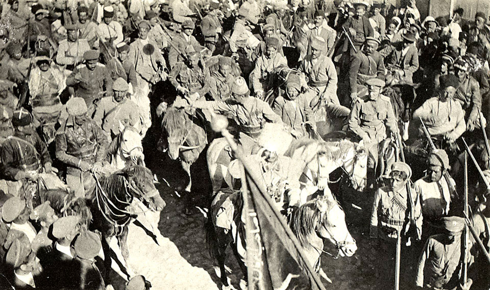 Assyrian troops led by Agha Petros (saluting) with a captured Turkish banner in the foreground, 1918