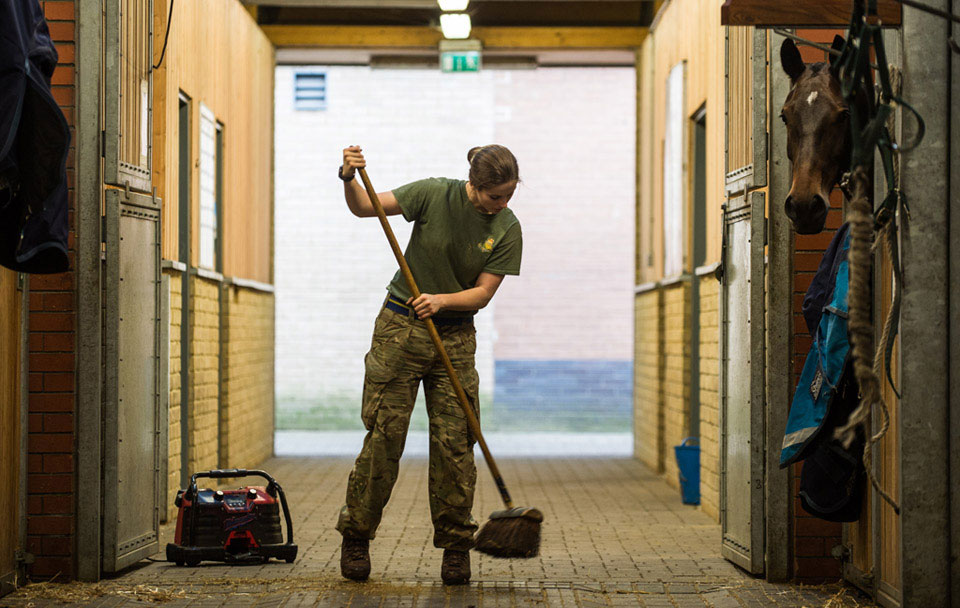 A gunner from King's Troop, Royal Horse Artillery sweeps a stable out while on Christmas Duty, Woolwich Barracks, 2015