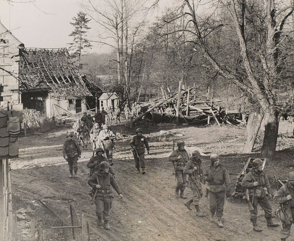 Soldiers of the US 7th Army move through a shell-torn village, 1944