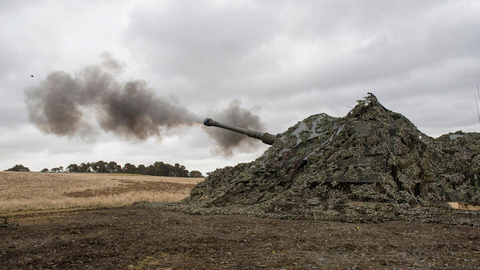 A camouflaged AS90 fires a 155 mm high explosive round, Otterburn Training Area, North Yorkshire, 2015