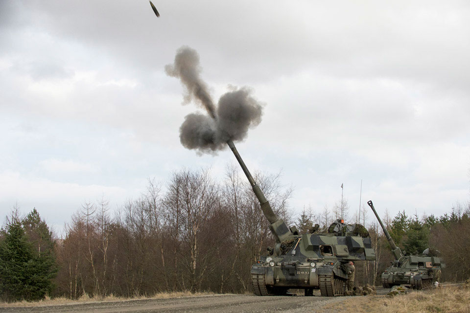 An AS90 self-propelled gun fires a 155 mm high explosive round in the high angle position, Otterburn Training Area, North Yorkshire, 2015