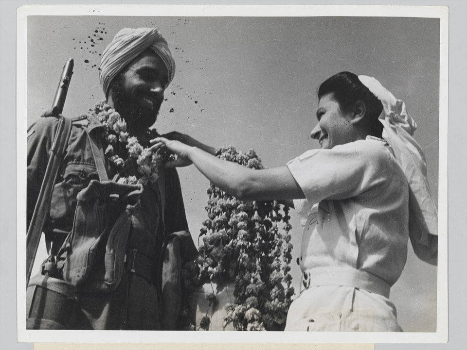 A Sikh soldier receives a garland of flowers from a nurse, 1946 (c)
